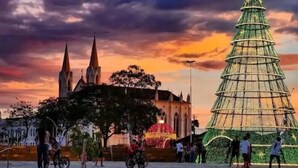 A large Christmas tree in front of a church with spires, set against a sunset sky. - Pousada Gama (Diamantina)