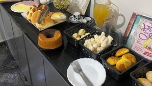 A buffet with various food items including bread, pastries, and a cake. - Pousada Gama (Diamantina)
