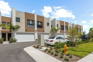 A modern multi-story residential building with a parking area and a fire hydrant.