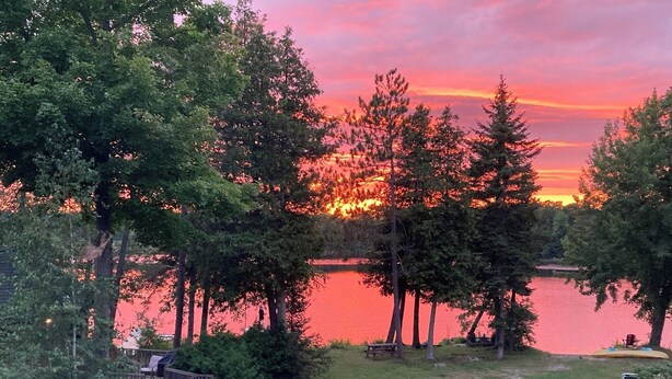 En vacker utsikt över sjön med en träbrygga, picknickbord och en klar himmel.