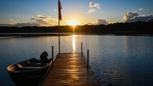 En träbrygga som sträcker sig ut i stilla vatten, med en båt förtöjd vid änden.