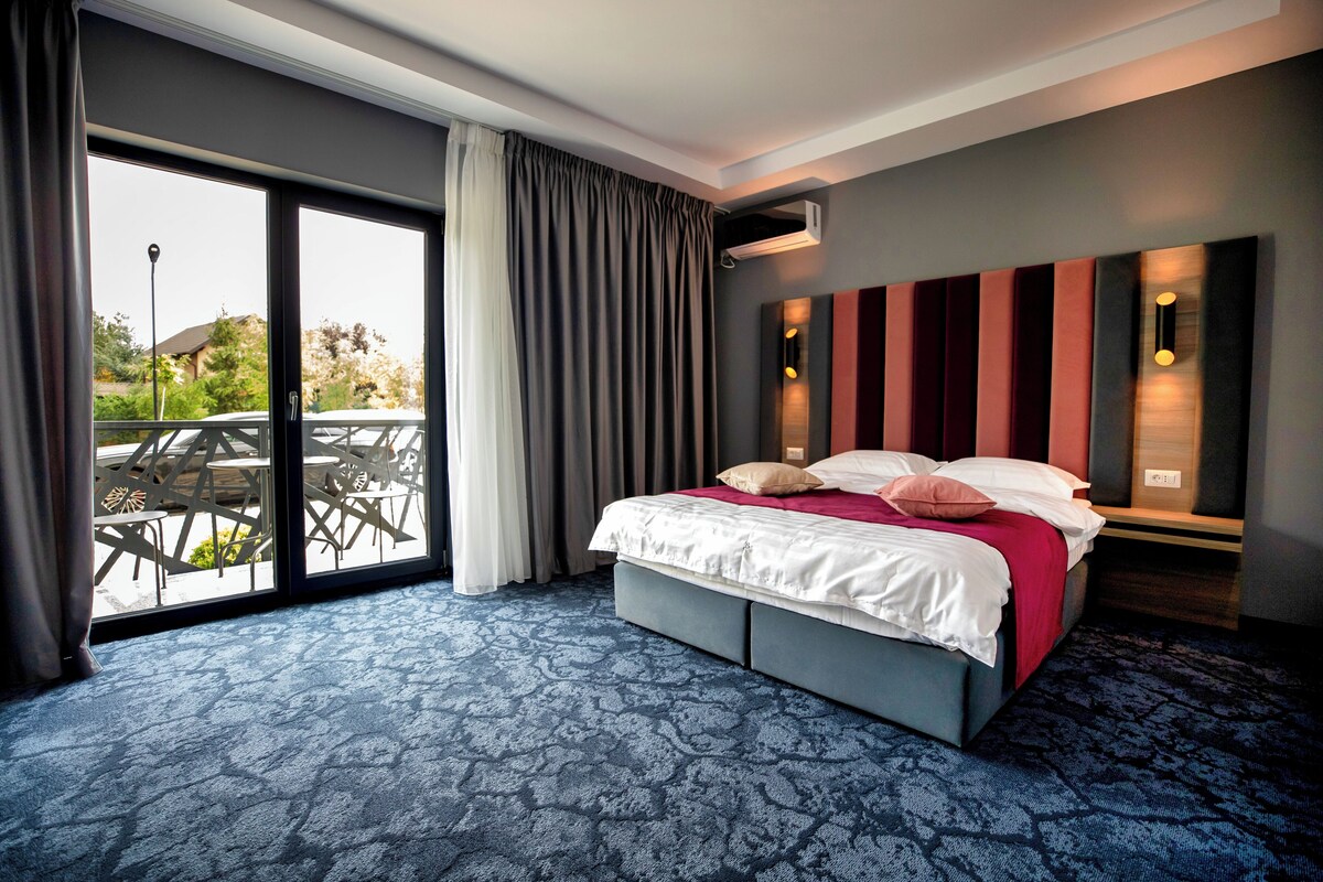 A hotel room with a large bed, a sliding glass door to the outside, and a view of the outdoors.