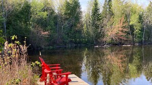 Un muelle de madera que se adentra en un lago tranquilo, rodeado de un bosque denso.