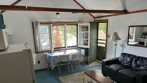 Une pièce comprenant une table à manger, des chaises, un canapé, une lampe et un réfrigérateur.