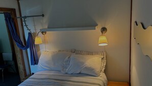 Une chambre à coucher avec un lit, deux lampes de chevet, une table de chevet en bois et un rideau.