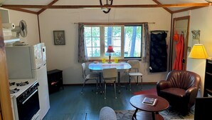 A compact living space with a kitchenette, a dining area, and a seating area with a sofa and a chair.