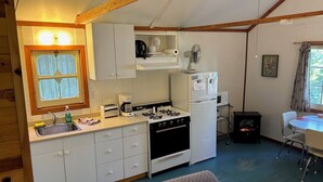 A compact kitchen with white cabinets, a gas stove, a refrigerator, and a microwave.