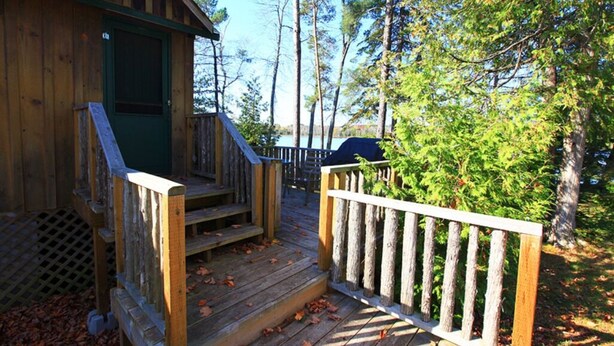 A wooden cabin with a porch and a fenced deck area.