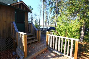 A wooden cabin with a porch and a fenced deck area. - Relaxing Hot Diggity Dog Cottage Retreat at the Lake Edge Cottages! (Lakefield)