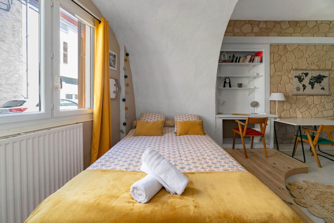 A bedroom with a bed, a desk, and a chair.
