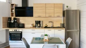 Een moderne keuken met houten kastjes, een zwarte afzuigkap en een roestvrijstalen koelkast.