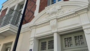 A building with a white facade, red brick accents, and a balcony with metal railings. - Air-cond and designer apartment (Vichy)