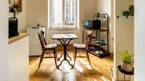 A compact kitchen with a dining table and chairs, a microwave, and a sink. - Le Cosy - 11 Rue de la Boucherie - Clermont (Clermont-Ferrand)