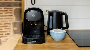A coffee maker, a kettle, and a bowl on a wooden countertop in a kitchen with white tiles and a stone wall. - Le Cosy - 11 Rue de la Boucherie - Clermont (Clermont-Ferrand)