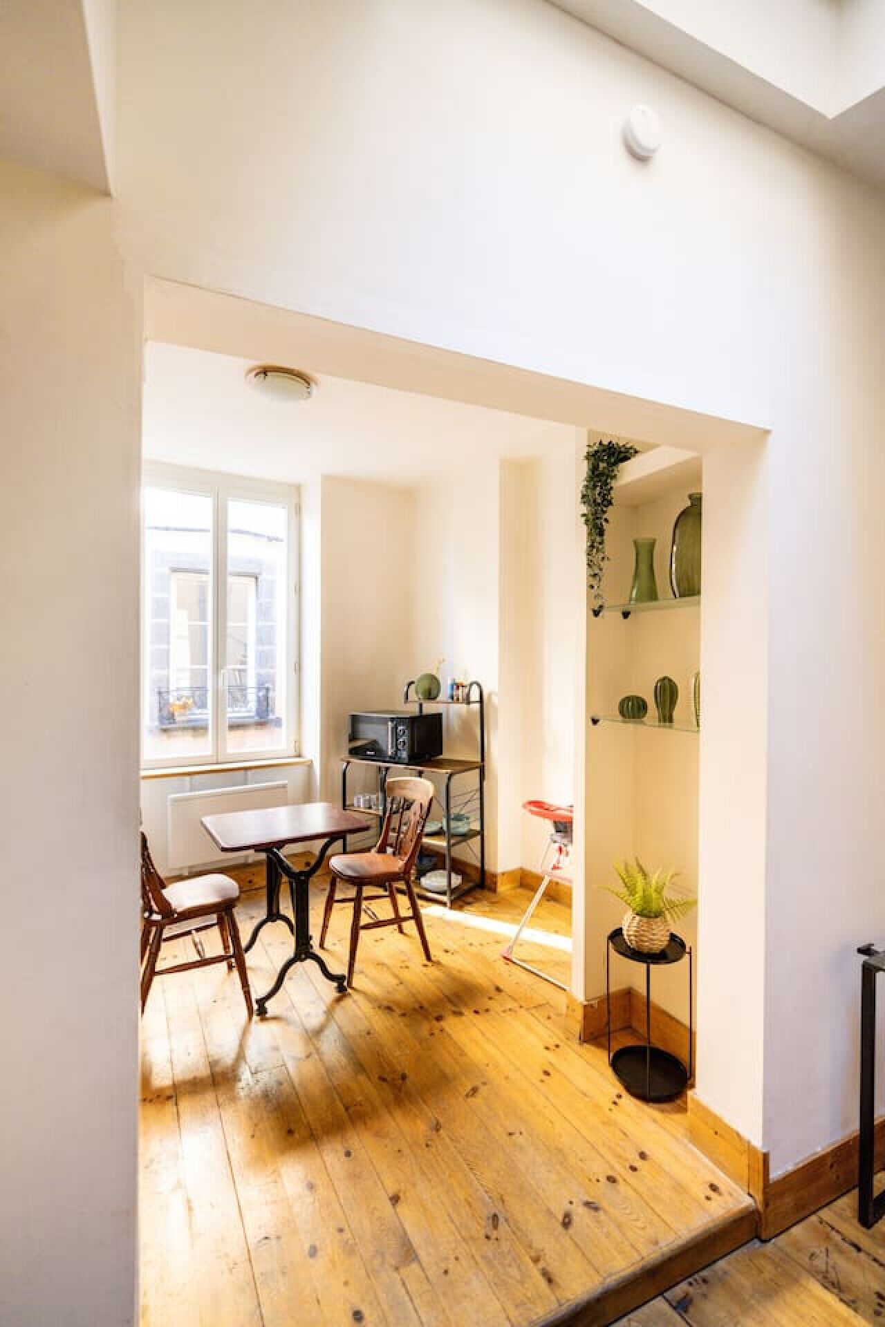 Un espacio habitable compacto con zona de comedor, microondas y una pequeña planta.