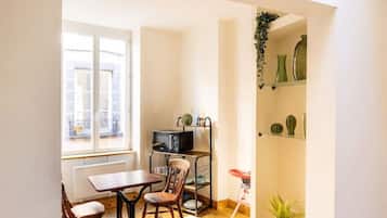 Un espacio habitable compacto con zona de comedor, microondas y una pequeña planta.