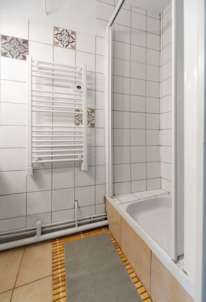 A shower area with a white tiled wall, a showerhead, and a towel rack. - T1 cocooning with terrace (Clermont-Ferrand)