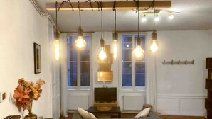 Een woonkamer met een houten tafel, een bank en hangende lampen.