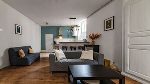 Een woonkamer met een bank, een salontafel en een keuken op de achtergrond.