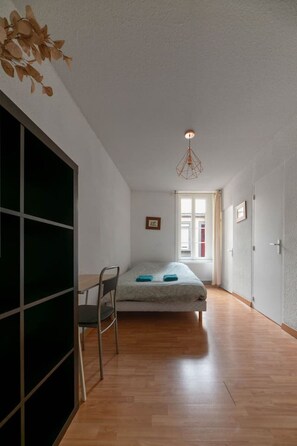 A bedroom with a bed, a chair, a desk, and a window. - T1 cocooning with terrace (Clermont-Ferrand)
