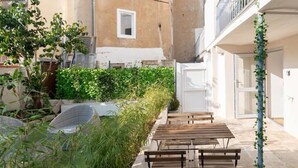 Ein Innenhof mit Sitzgelegenheit, einem kleinen Garten und einem Gebäude mit Balkon.
