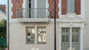 Ein zweistöckiges Gebäude mit Balkon, Schornstein und einer symmetrischen Fassade.