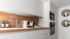 Eine moderne Küche mit weißen Schränken, einer Holz Arbeitsplatte, einer Edelstahl-Spüle und einem eingebauten Backofen.