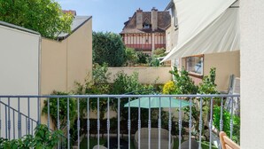 A courtyard with a white umbrella, wicker furniture, and a metal railing. - Le Jaures RdC - 41 rue Jean Jaures - Vichy (Vichy)