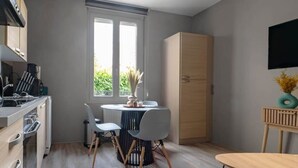 A modern kitchen with a dining area, a large window, and a flat-screen TV.