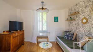 Un salon chaleureux avec un meuble en bois, un téléviseur, une table basse ronde, un canapé et une fenêtre avec des rideaux.