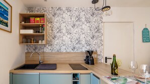 Une cuisine avec un plan de travail en bois, un évier et une étagère contenant des ustensiles de cuisine.