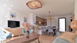 A modern living room with a wooden coffee table, a sofa, and a dining area with chairs and a table. - Cancale à la plage - Maison avec terrasse pour 6 (Cancale)