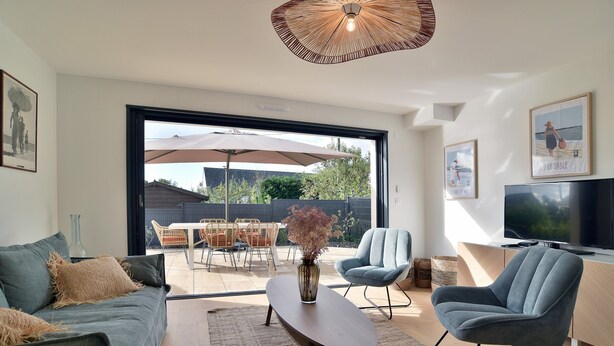 A modern living room with a sofa, armchair, coffee table, and a TV. - Cancale à la plage - Maison avec terrasse pour 6 (Cancale)
