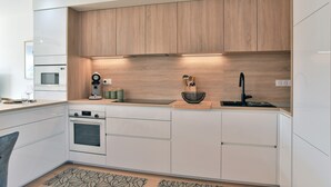 A modern kitchen with white cabinetry, a wooden countertop, and a built-in oven. - Cancale à la plage - Maison avec terrasse pour 6 (Cancale)