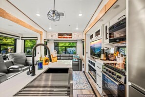 Interior moderno de una casa rodante con cocina, comedor y zona de estar.
