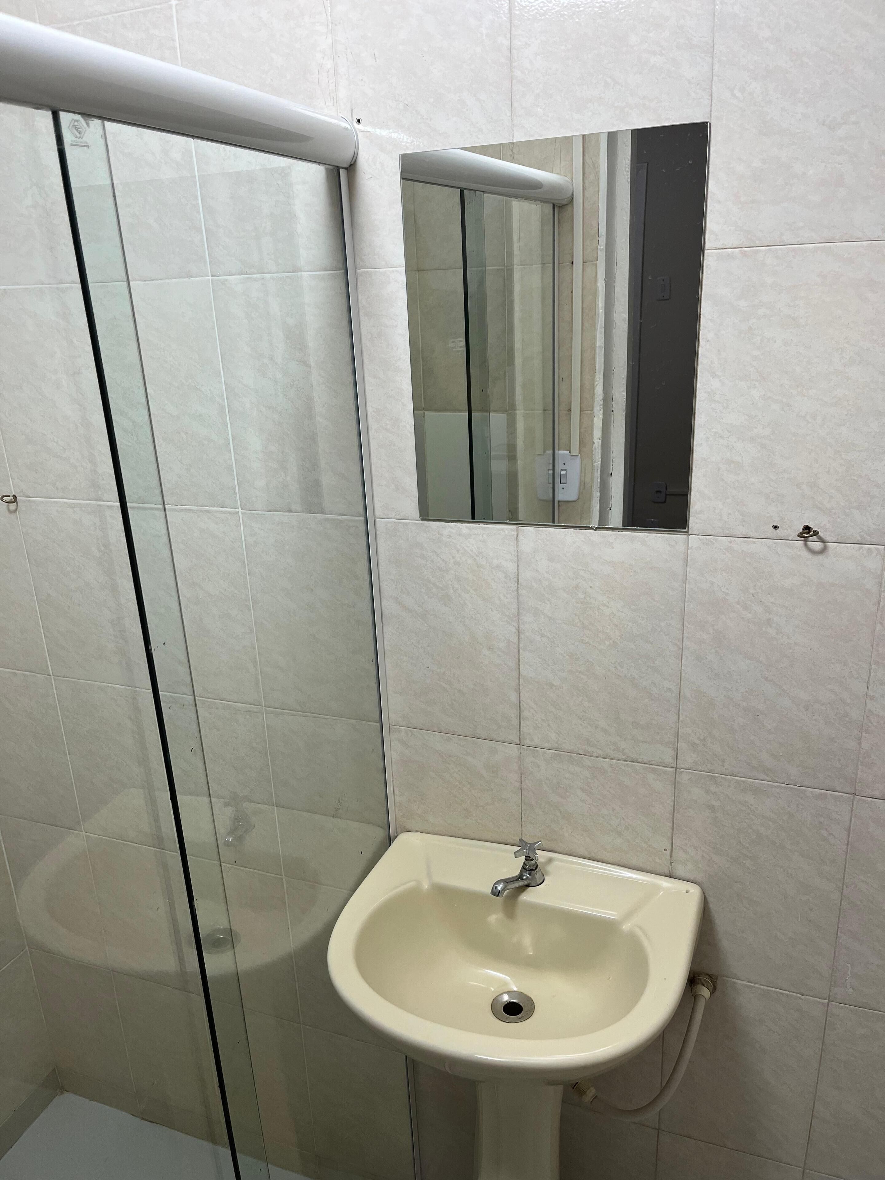 Un baño con lavamanos blanco, cabina de ducha de vidrio y un espejo.
