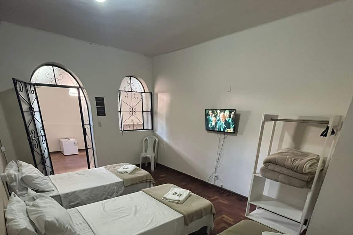 A hotel room with two beds, a TV, a wardrobe, and a small window.