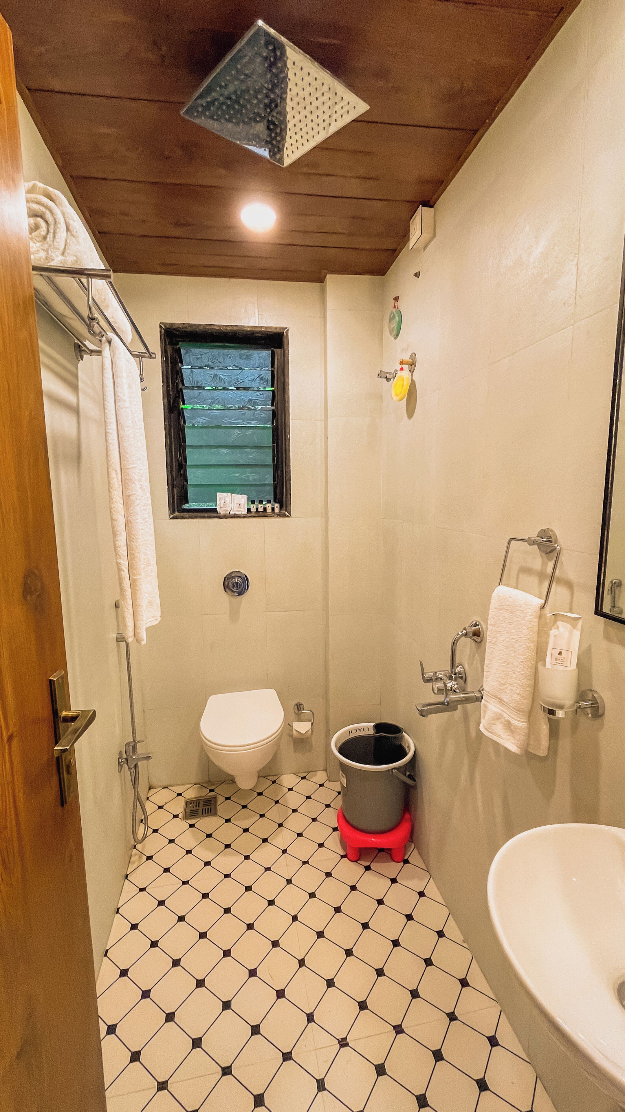 A bathroom with a toilet, sink, shower, and a window.