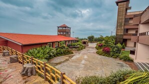 A courtyard with a stone pathway, wooden fence, and various plants. - Regenta Bharti Amusement & Adventure Resort Pune, Urulikanchan (Daund)