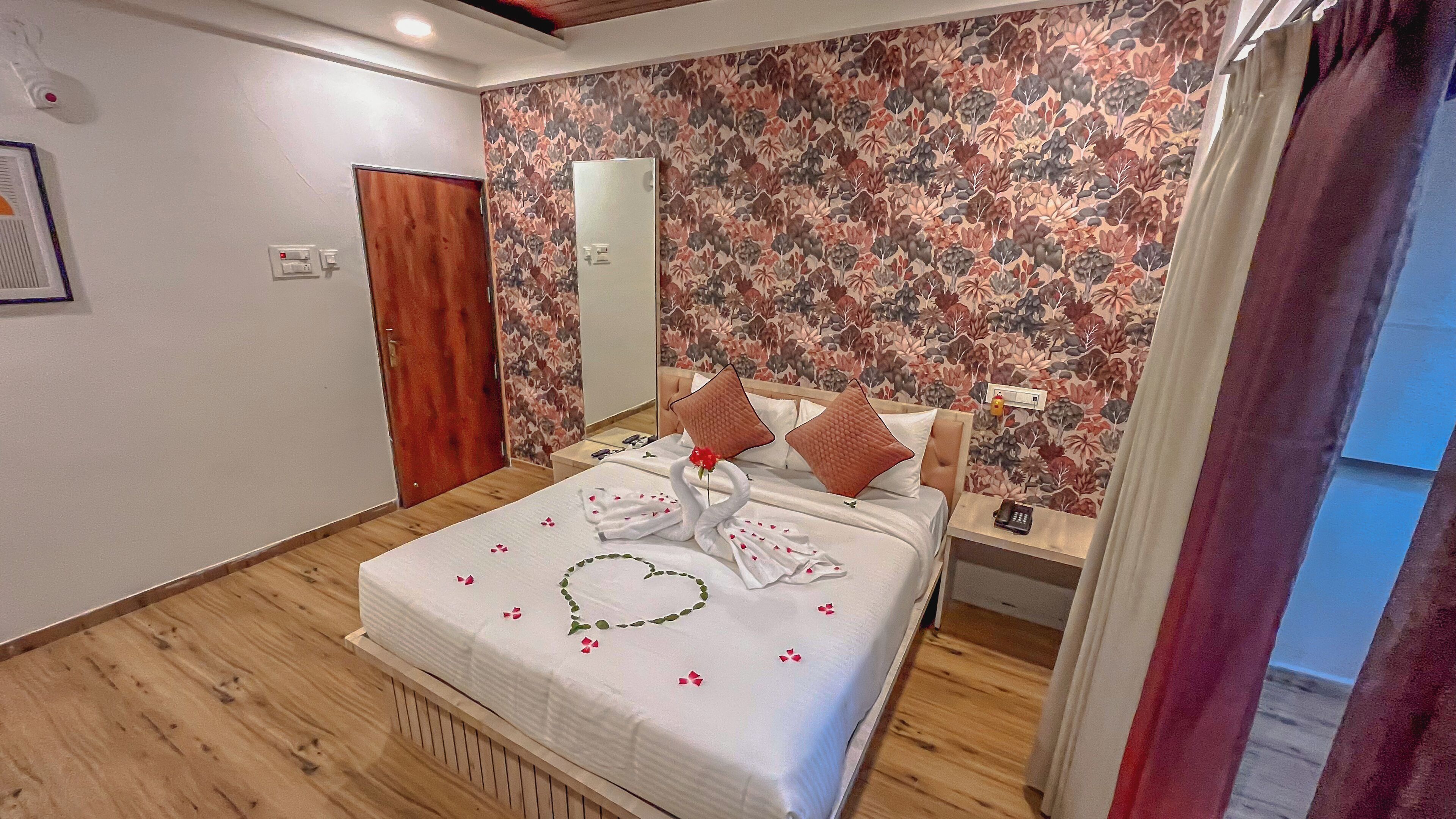 A neatly made bed with a floral wall and a wooden floor.