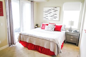 Relax in a serene bedroom with a large bed, wall-mounted artwork, and a nightstand with a lamp.