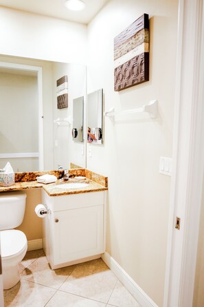 Bathroom features a toilet, sink with granite countertop, and a mirror above the sink.
