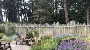A garden with wooden furniture and a wooden fence. - North Shore Retreat: Private Beach Access, Tennis/Pickleball Court, Pets Welcome (Eastsound)