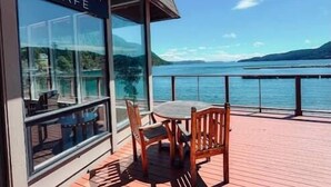 A deck with a table and chairs, a sign reading 'BLACKFISH CAFE,' and a view of a body of water. - Historic Waterfront Home, Hot tub, Pets Welcome! (Eastsound)