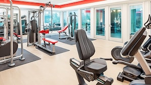 A modern gym with various exercise equipment, large windows, and ceiling fans. - Sunshine Stay | 2BR Galleria Apartment Nr Mall (Houston)