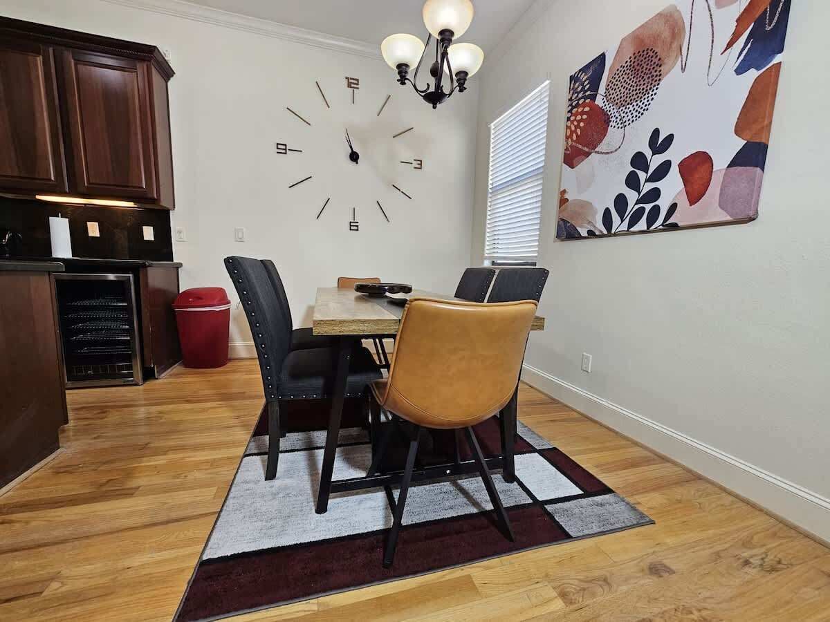 A dining area with a wooden table, chairs, a clock, and a decorative wall piece.