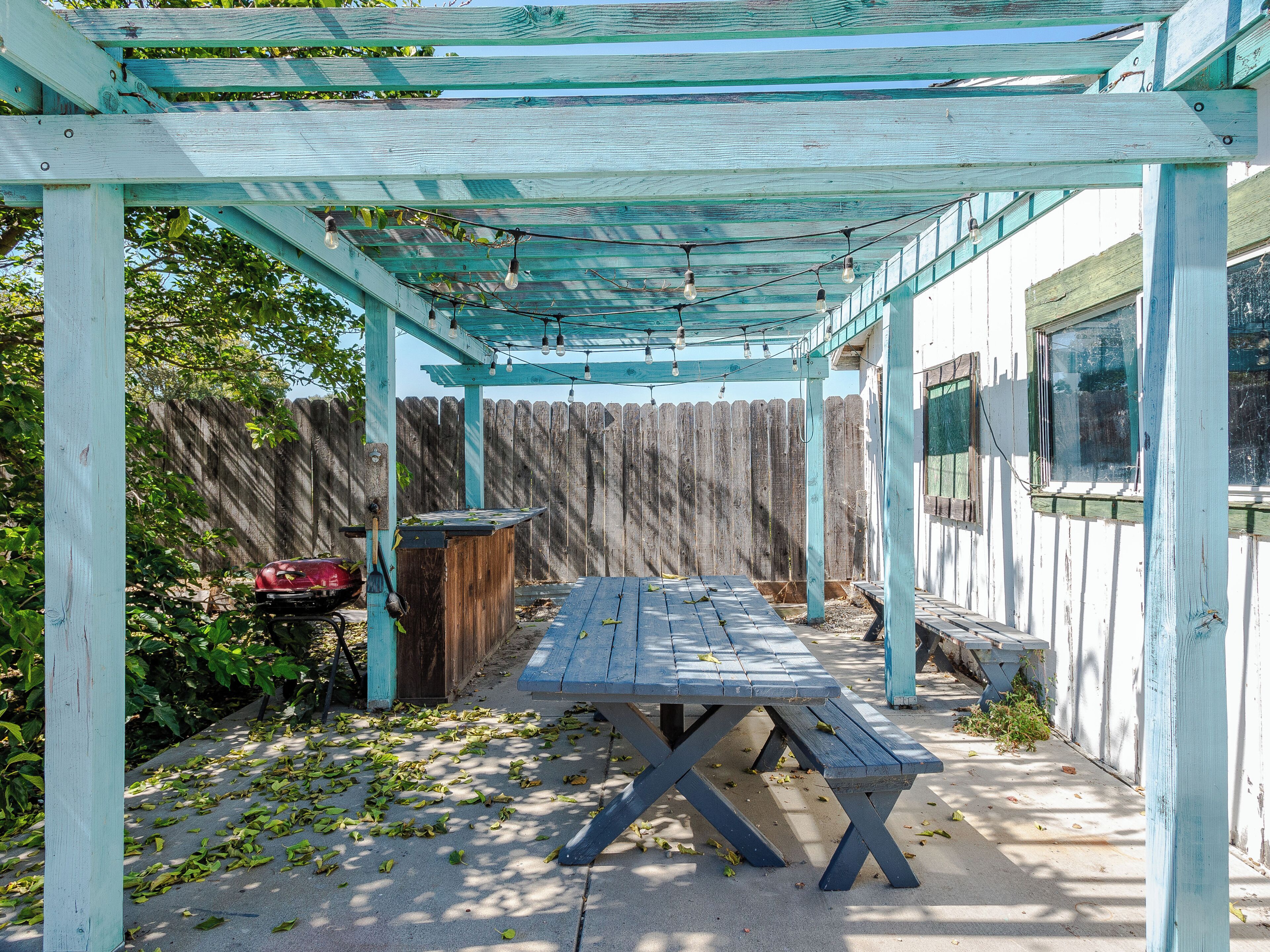 A covered patio area with a picnic table and string lights.