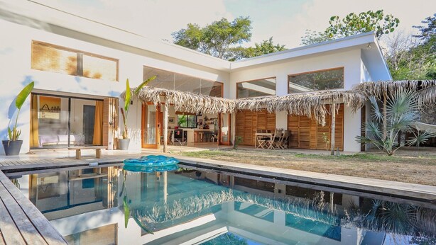 Ein modernes Haus mit Pool, Essbereich und überdachter Terrasse.
