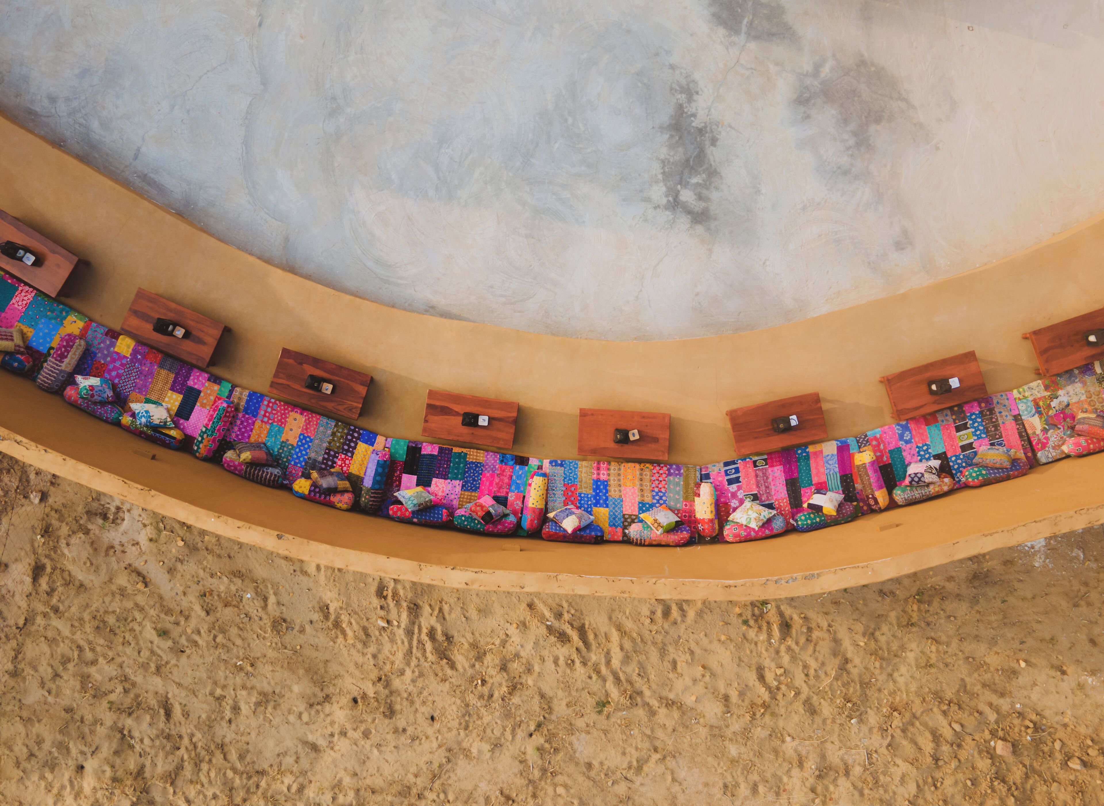 A curved pool with a colorful quilted edge and wooden boxes along the side.