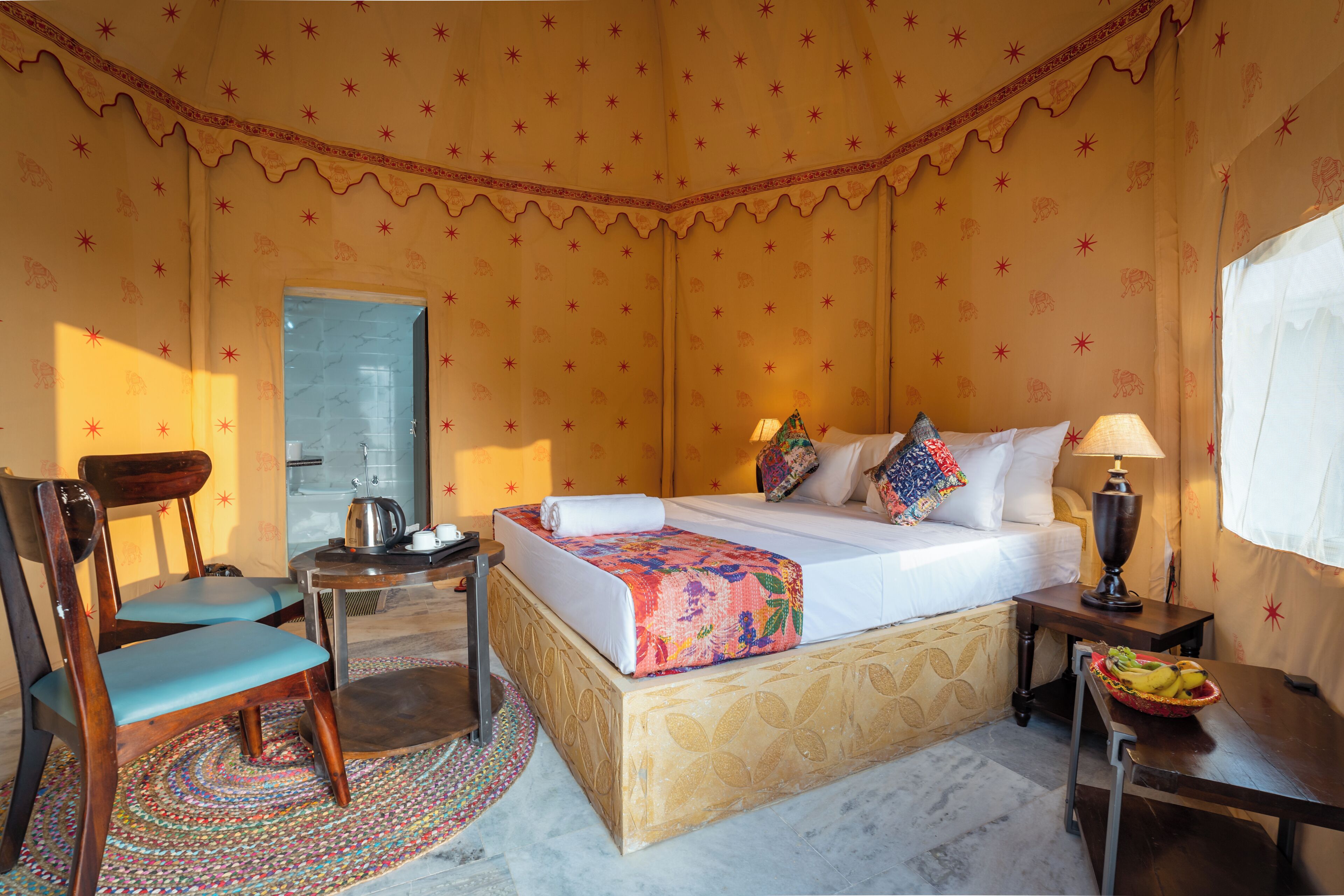 A room with a bed, a chair, a table, and a lamp.